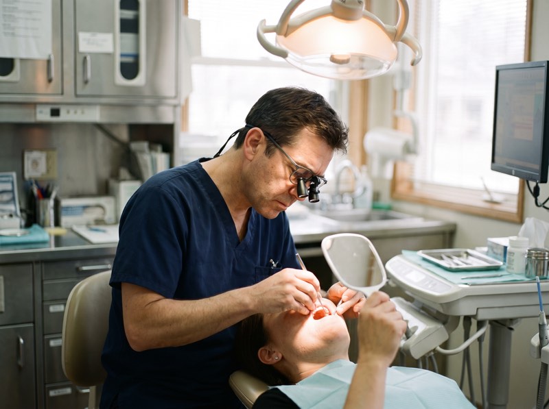 A dentist examining a patient's teeth with a mirror